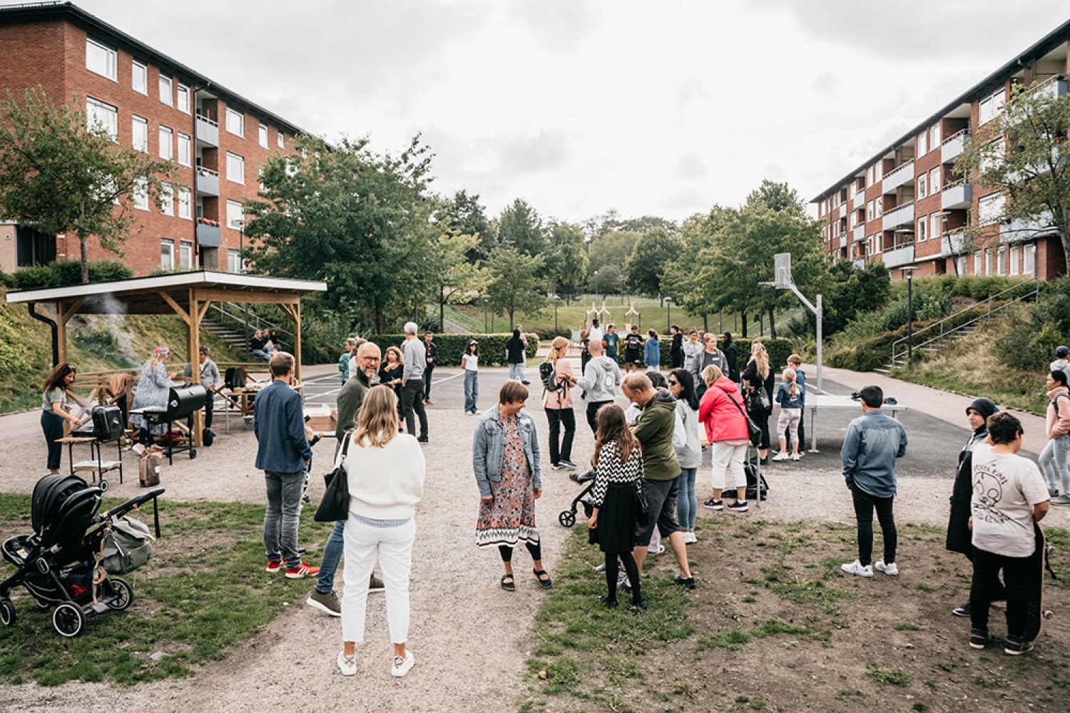 Många människor på Communityskolan Tynnereds skolgård grillar hamburgare och umgås.