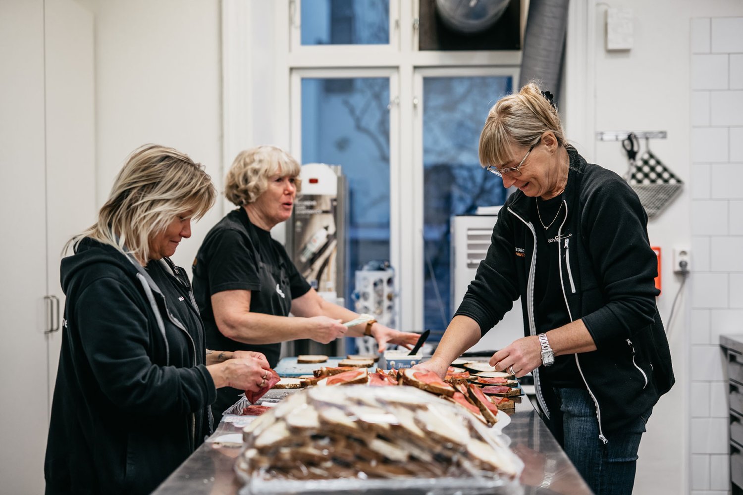 Tre personer förbereder frukost till gästerna på Räddningsmissionens frukostcafé för människor i hemlöshet.