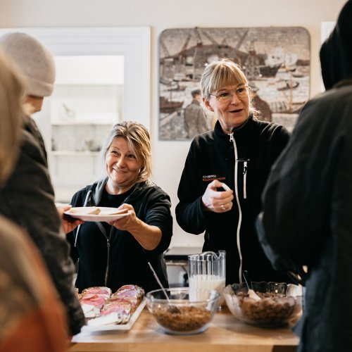 Två glada medarbetare serverar frukost till personer i hemlöshet på Räddningsmissionens frukostcafé.